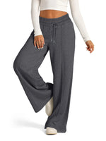 Person wearing gray wide-leg pants with a white top on a white background