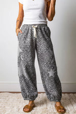 Person wearing gray leopard print pants with a white top against a plain background