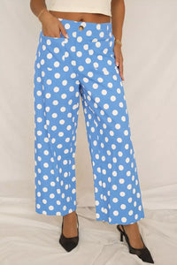 Blue pants with white polka dots worn by a person on a light gray background
