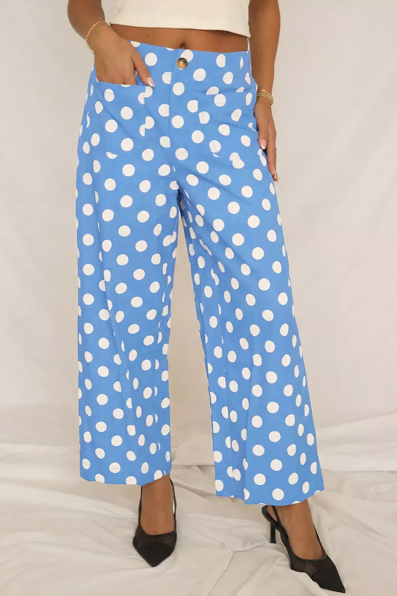 Blue pants with white polka dots worn by a person on a light gray background