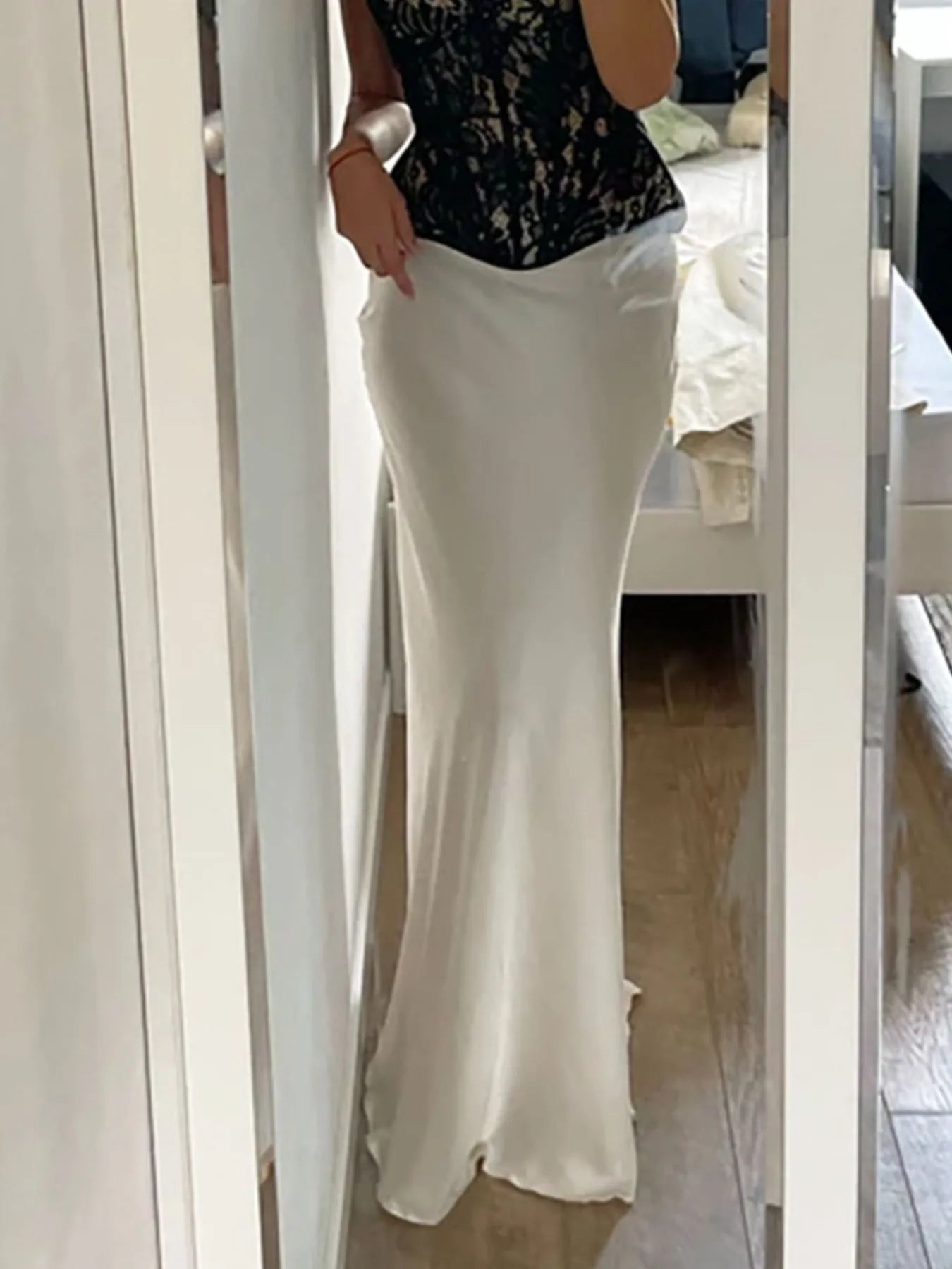 Person wearing a black top and white pants standing in front of a mirror.