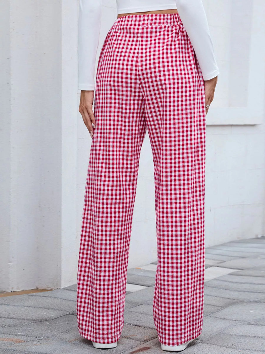 Red and white checkered pants worn by a person against a white wall.