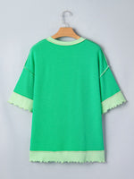 Green dress with light green trim on a hanger against a gray background