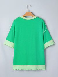 Green dress with light green trim on a hanger against a gray background