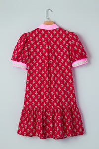 Red floral dress with pink trim on a hanger against a gray background