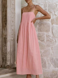 Woman wearing a pink dress standing against a stone wall.