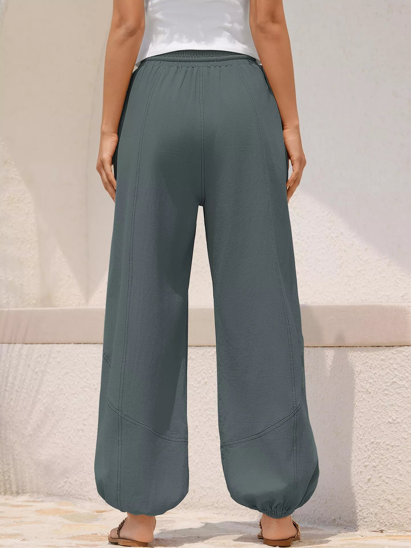 Person wearing teal wide-leg pants against a neutral background