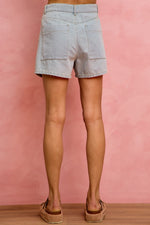 Light blue denim shorts worn by a person on a pink background