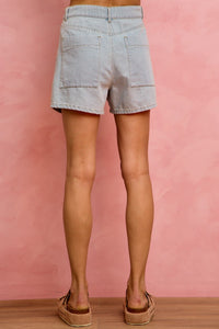 Light blue denim shorts worn by a person on a pink background