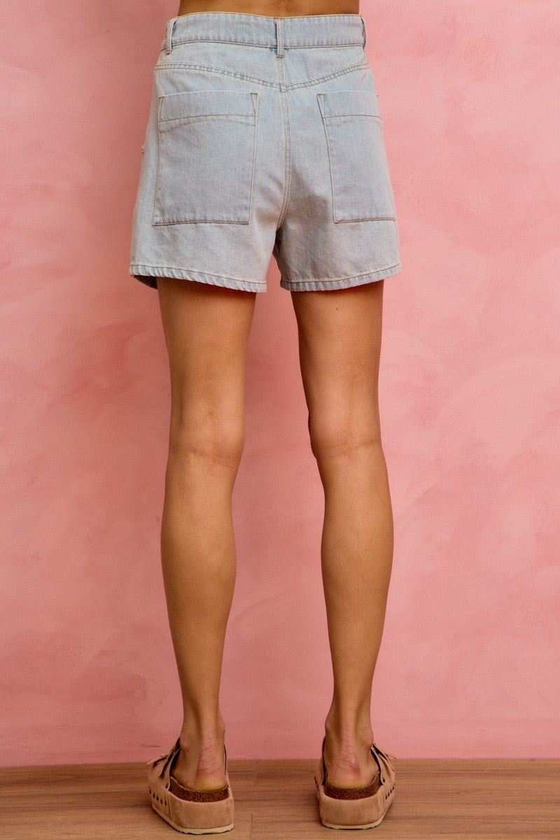 Light blue denim shorts worn by a person on a pink background