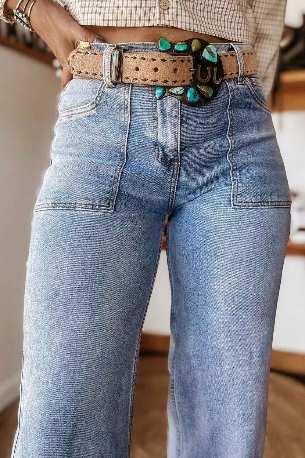 Person wearing blue jeans with a decorative belt