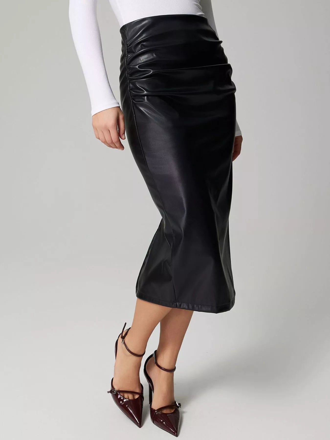 Person wearing a black leather skirt on a gray background
