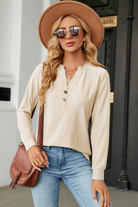 Woman wearing a beige blouse, blue jeans, and a brown hat with sunglasses outdoors.