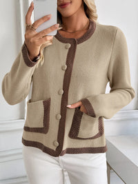 Woman wearing a beige cardigan with brown accents, taking a selfie.