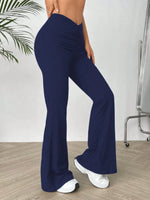 Navy blue flared pants worn by a person on a wooden floor with a white wall background.