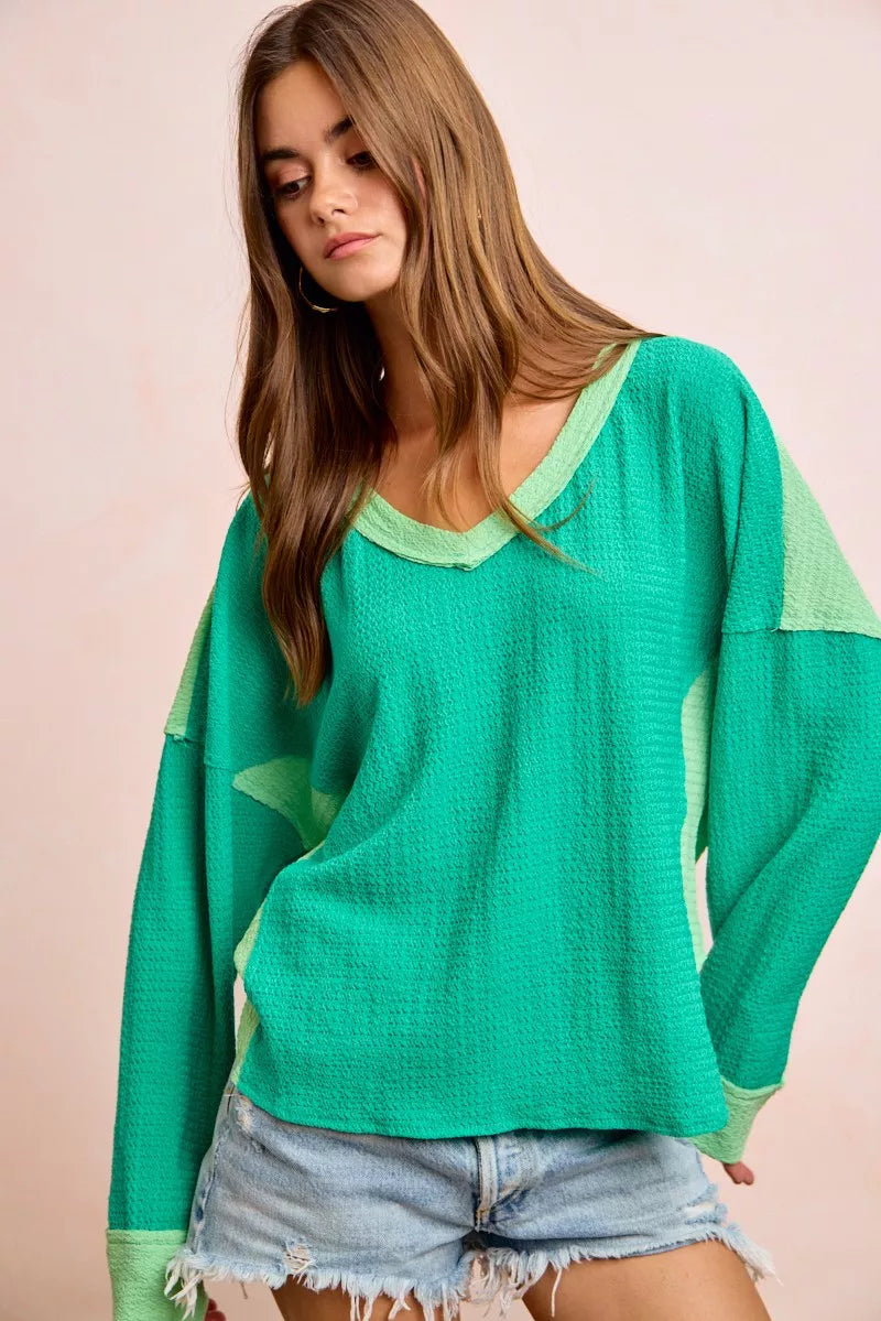 Woman wearing a green long-sleeve top with a plain background
