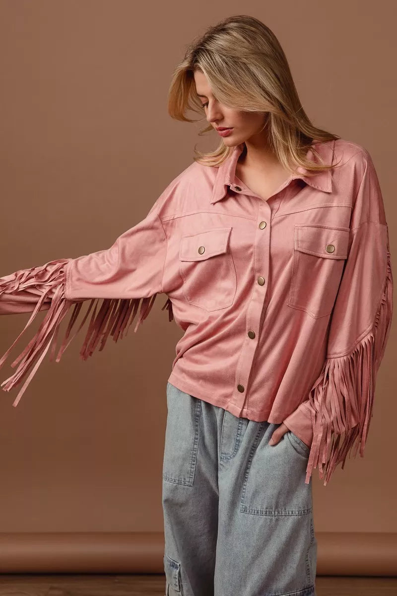 Woman wearing a pink fringed shirt against a brown background