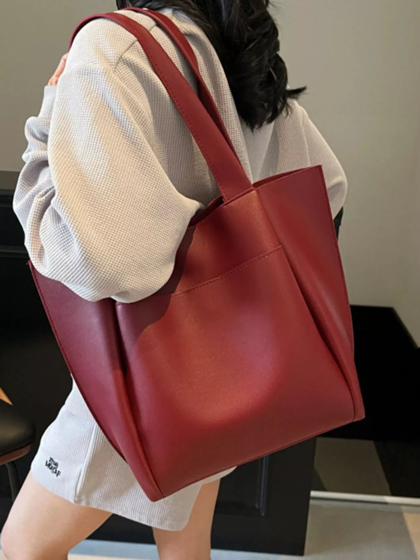 Person holding a red tote bag in an indoor setting