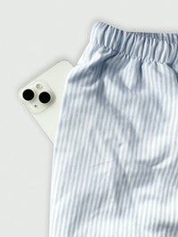 Blue and white striped pants on a light gray background with a smartphone.