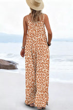 Person wearing a long floral dress and straw hat on a beach.