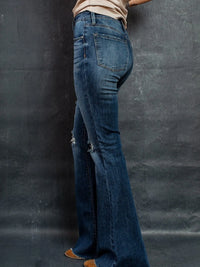 Person wearing blue flared jeans against a black background