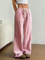 Person wearing pink striped pants with a white top in a minimal indoor setting.