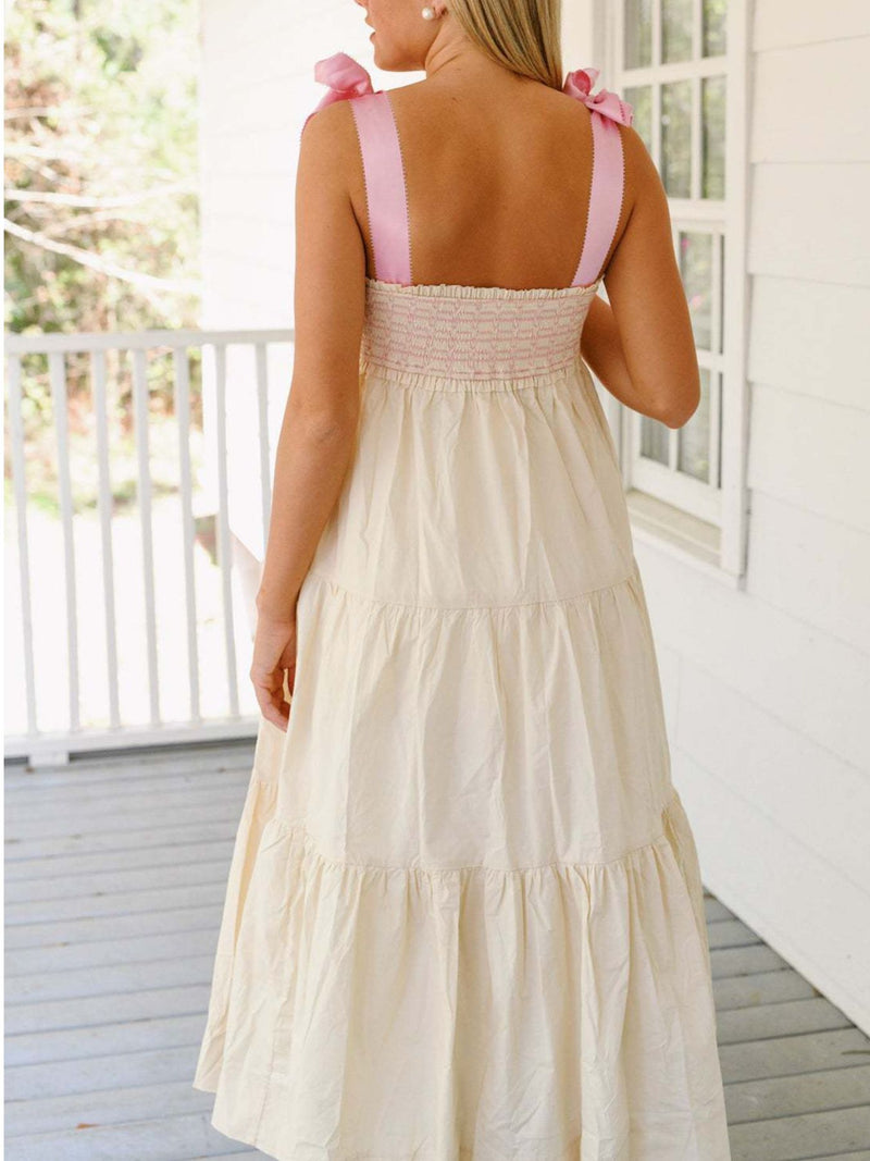Woman wearing a cream dress with pink straps on a porch.