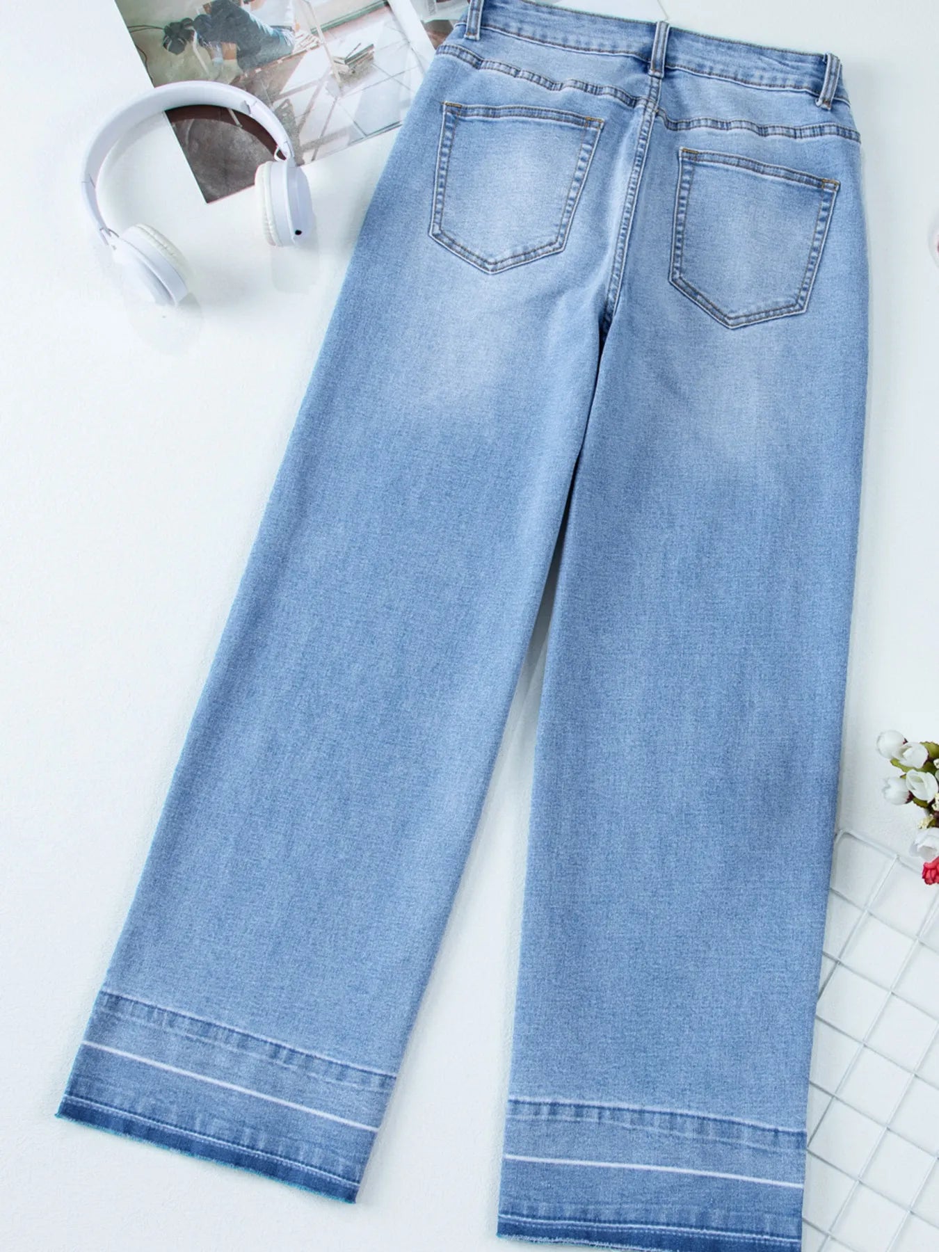 Light blue jeans on a white surface with a blurred background