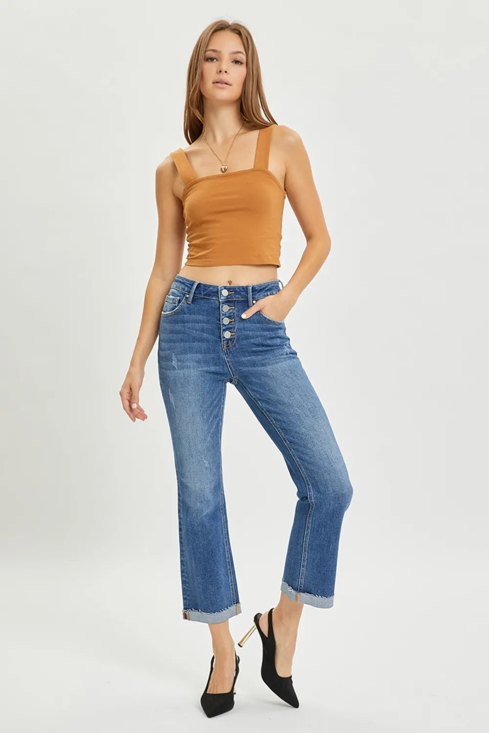 Woman wearing a brown top and blue jeans on a white background