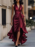 Woman wearing a burgundy halter neck dress with a high slit on a city street.