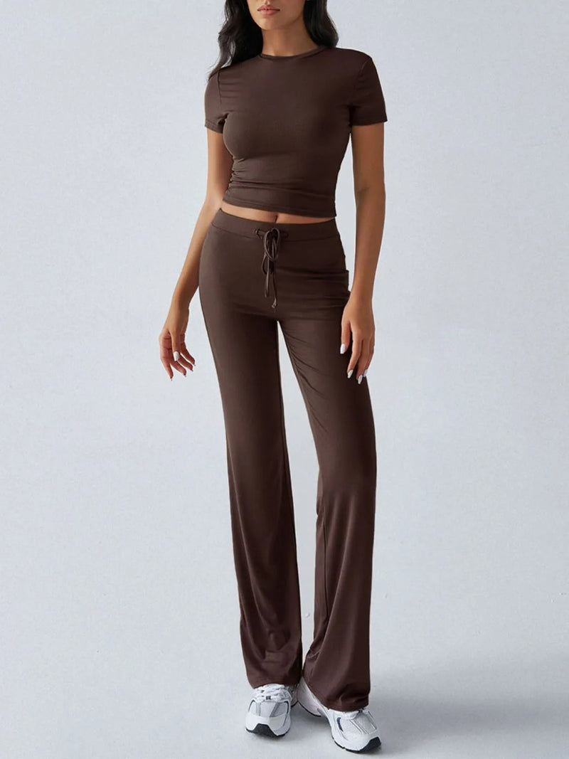 Woman wearing a brown outfit with a top and wide-leg pants on a light gray background