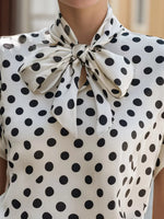 Polka dot blouse with a large bow neckline.