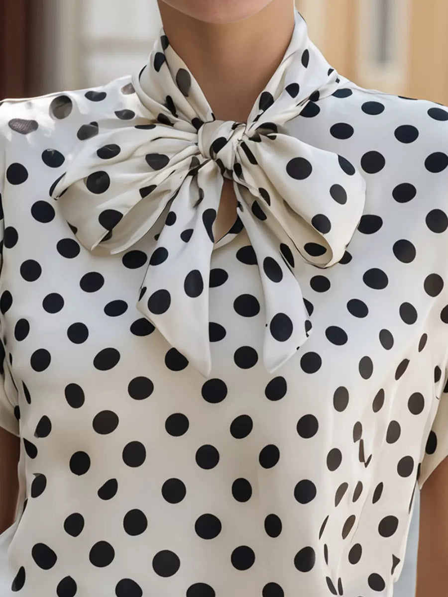 Polka dot blouse with a large bow neckline.