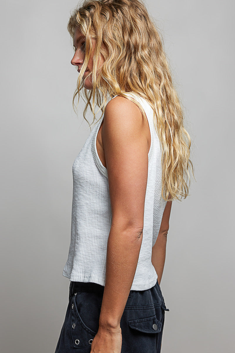 Woman wearing a sleeveless top and dark pants against a plain background