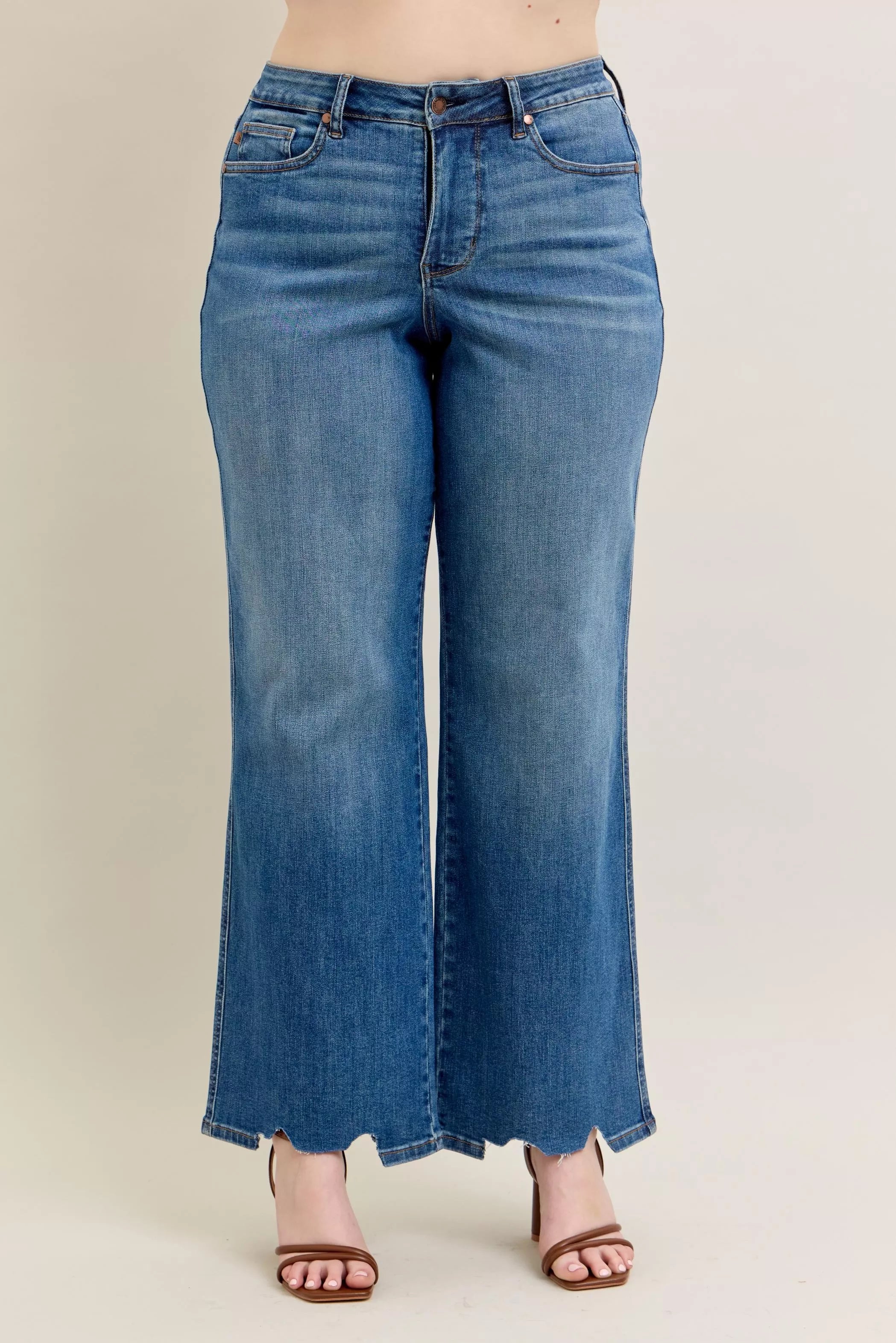 Blue jeans worn by a person on a plain background
