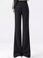 Black wide-leg trousers shown on a model from the waist down, paired with a gray long-sleeve top and white sneakers against a plain white studio background.
