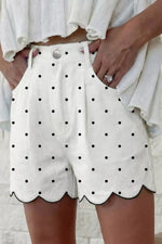 White shorts with black polka dots worn by a person against a light background