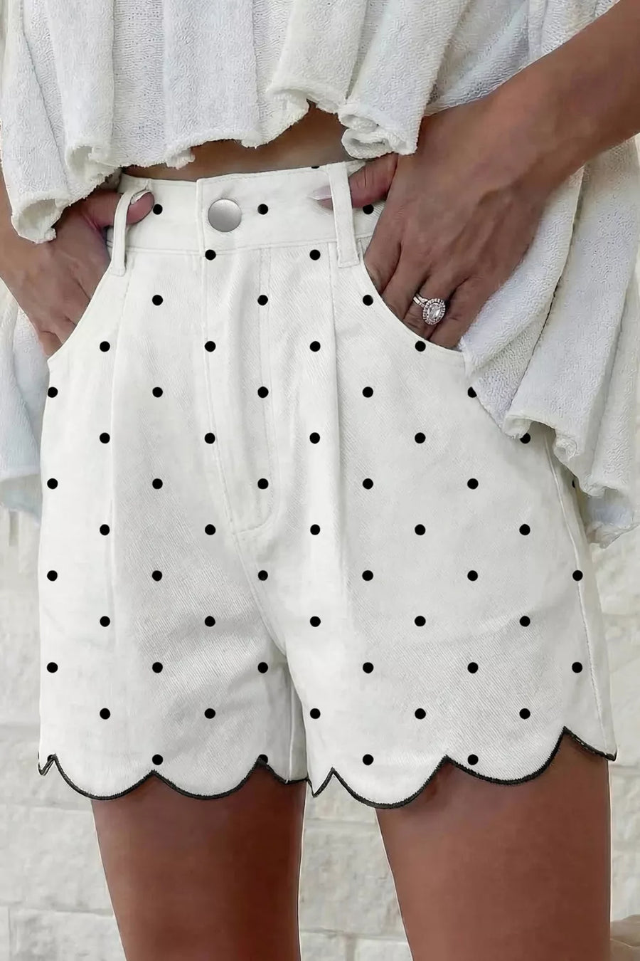 White shorts with black polka dots worn by a person against a light background