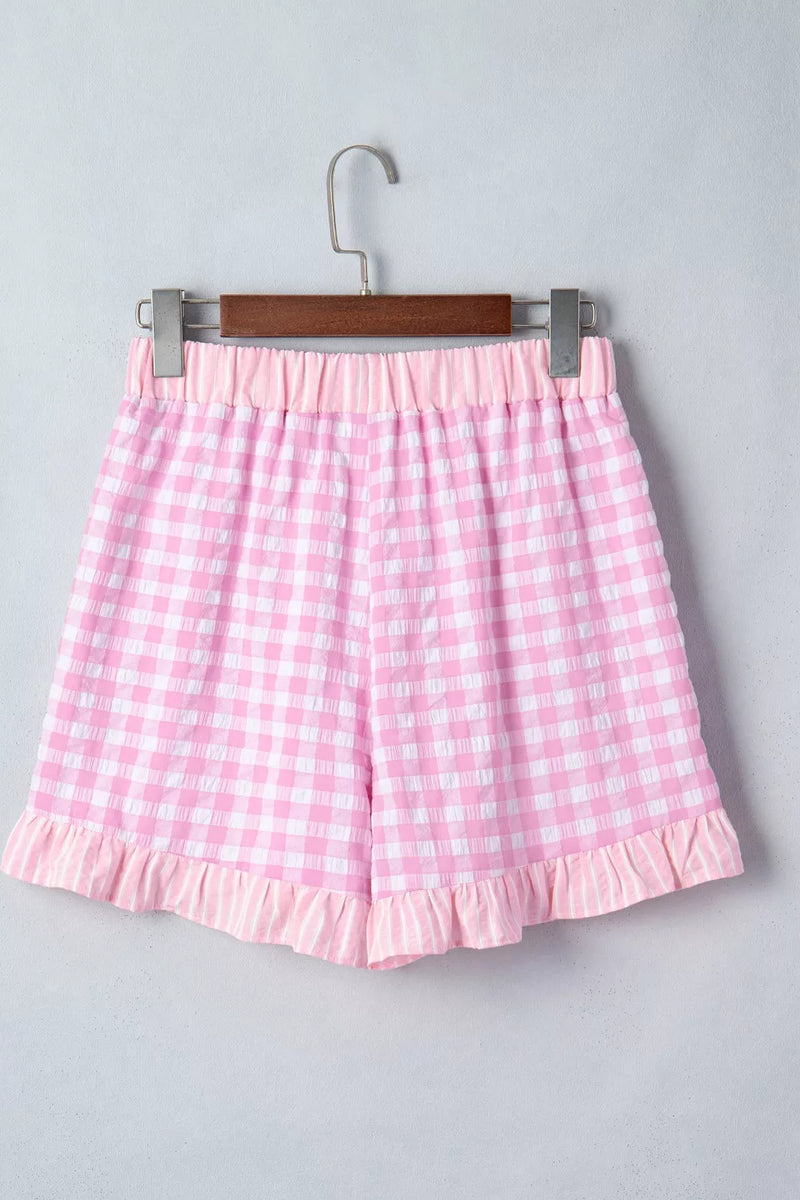 Pink gingham shorts on a hanger against a gray background