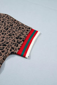 Leopard print glove with red, green, and white striped cuff on a light blue background