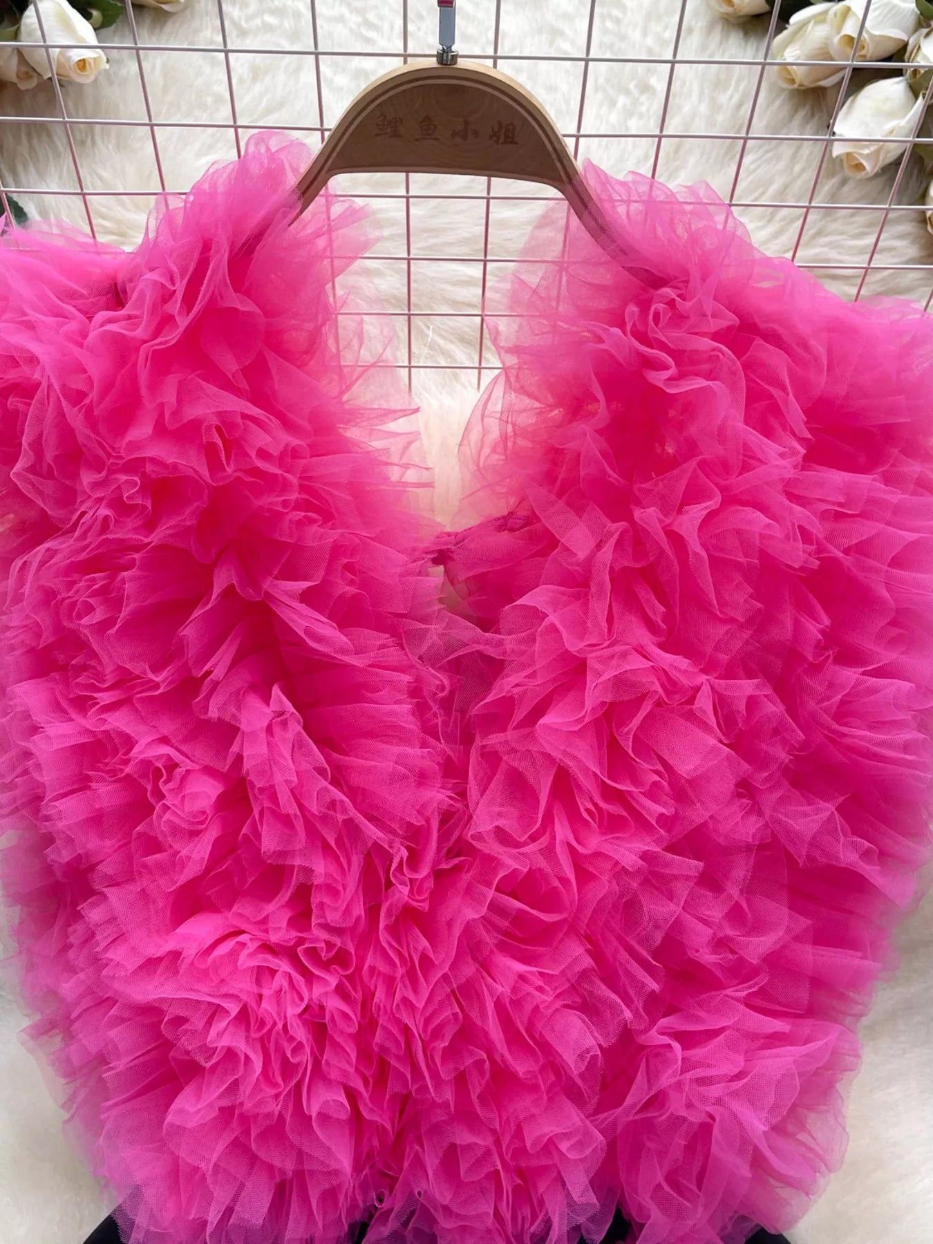 Pink fluffy garment on a hanger against a white background