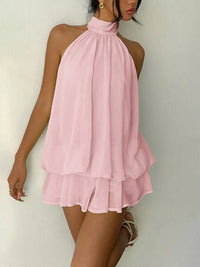 Pink halter dress worn by a person on a white background