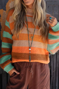 Person wearing a colorful striped sweater with a neutral background