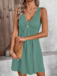 Woman wearing a green dress holding a brown bag against a neutral background