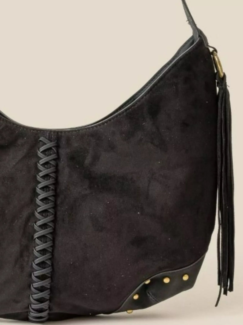 Black handbag with braided strap and tassel on a beige background