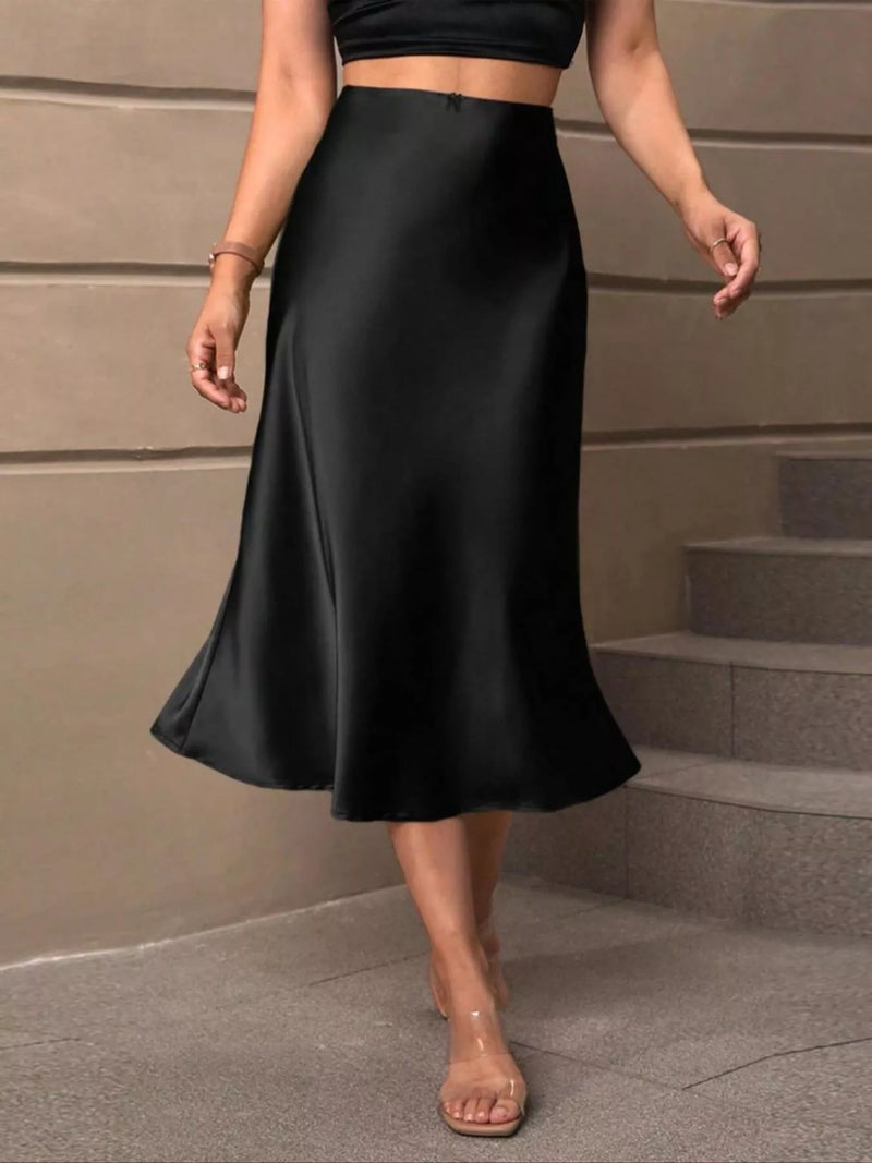 Person wearing a black skirt standing on steps with a neutral background