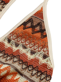 Close-up of a patterned sandal with orange, brown, and beige colors on a white background.