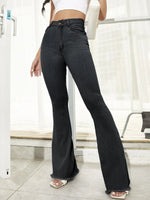 Person wearing black flared jeans in a minimal indoor setting