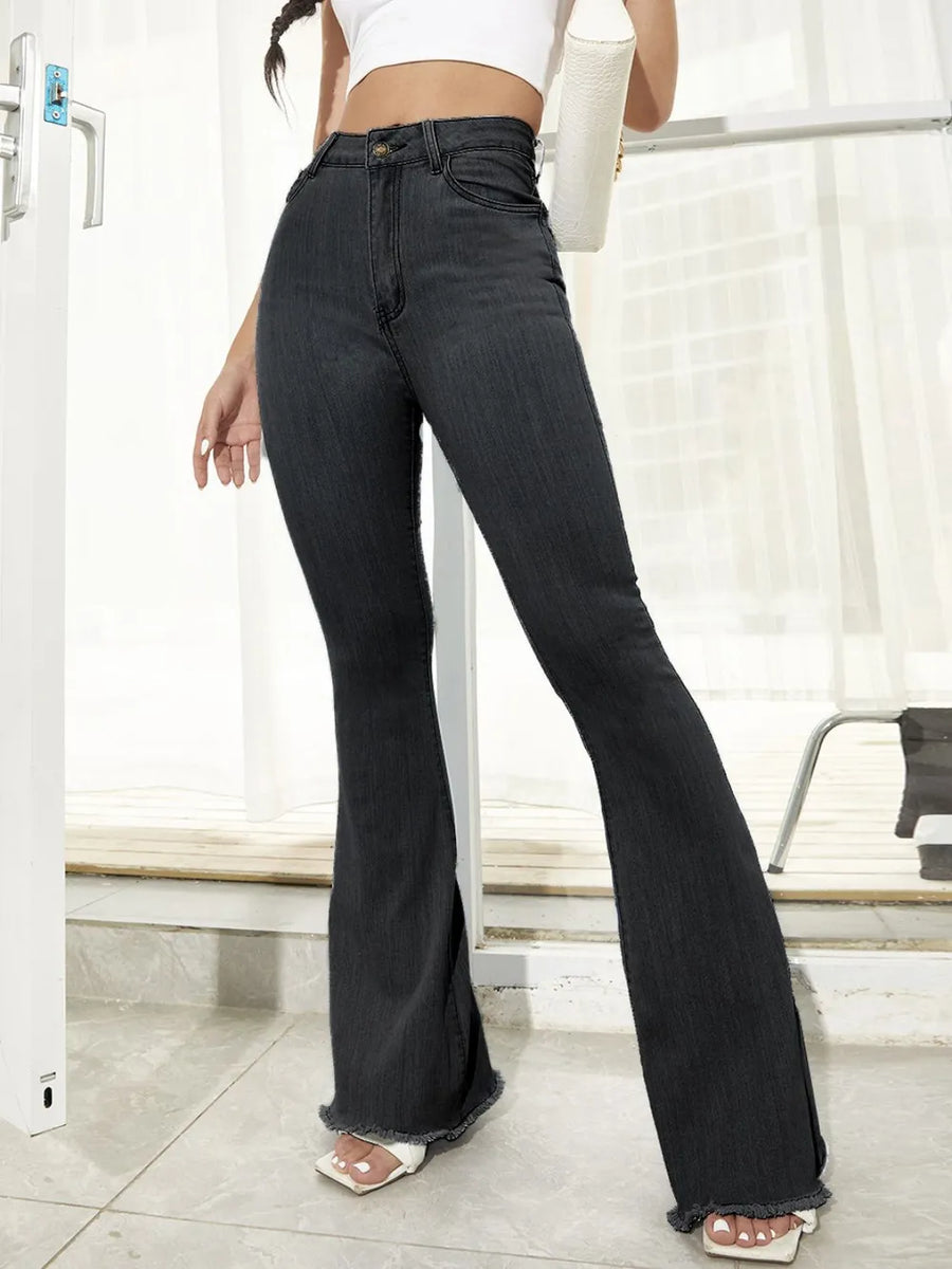 Person wearing black flared jeans in a minimal indoor setting