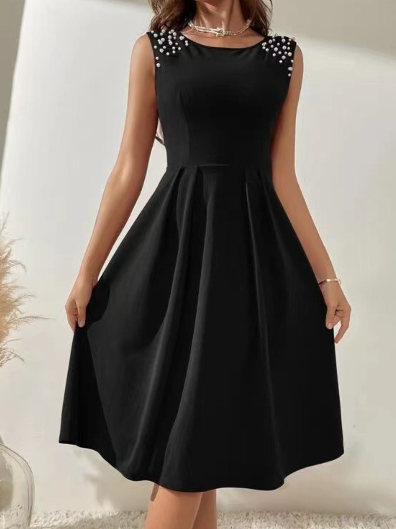 Black dress with pearl shoulder details on a white background